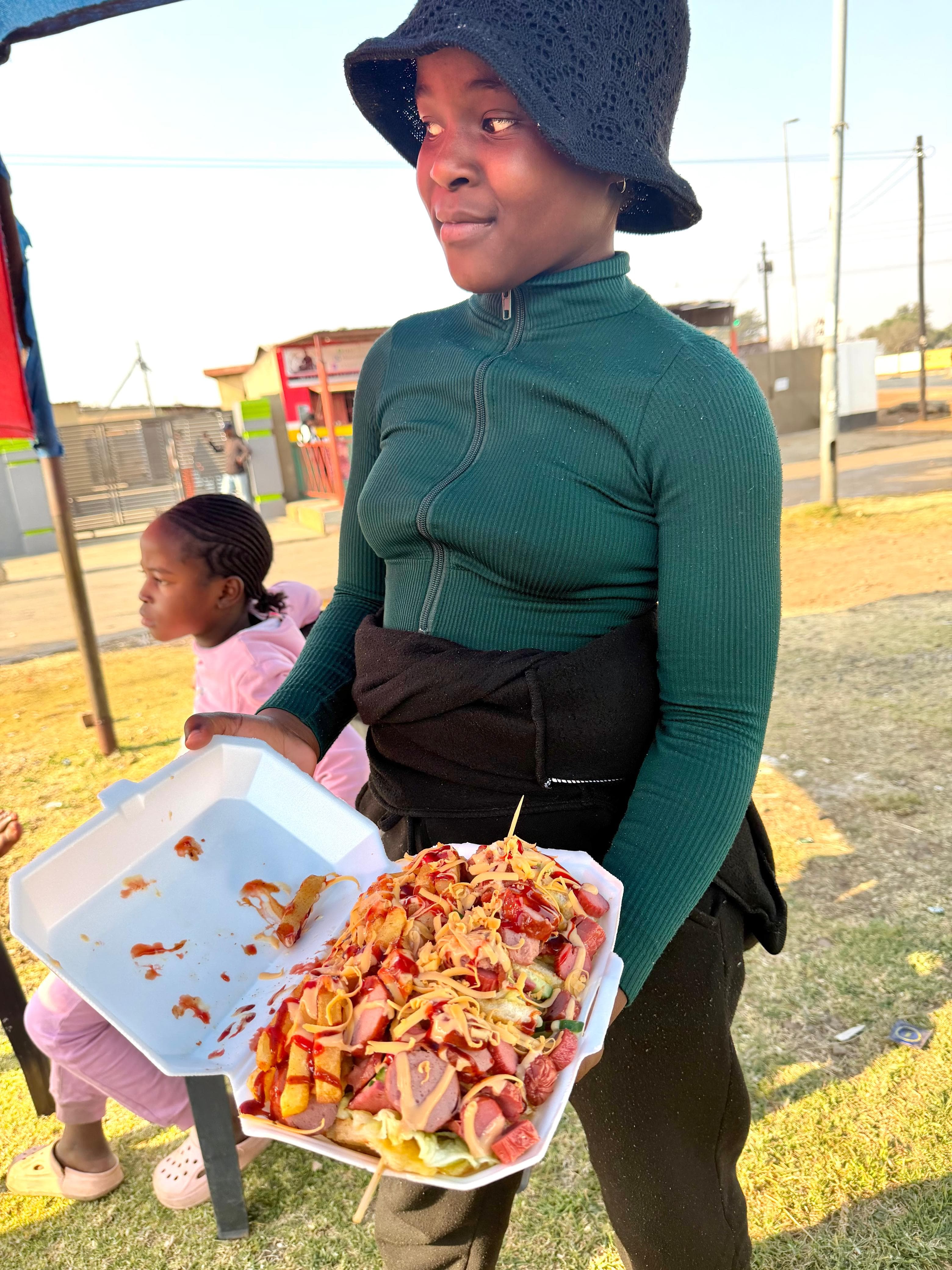 Young customer holding a loaded Vhadzanani Kitchen meal
